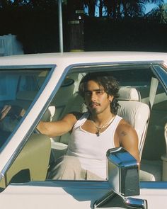 a man sitting in the driver's seat of a white car