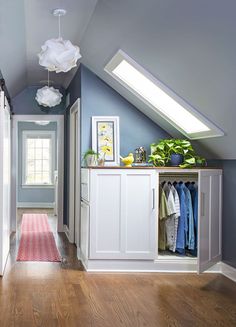 an attic bedroom with blue walls and white cabinets, hardwood floors, and skylights