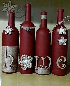 three red wine bottles decorated with flowers and monogrammed ribbons are sitting on a shelf