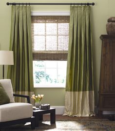 a living room filled with furniture and a window covered in green drapes next to a lamp