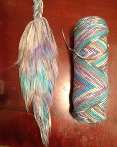 two skeins of yarn on a table next to a ball of yarn with feathers