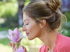 a woman smelling a flower with her eyes closed