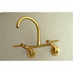 a gold faucet mounted to the side of a wall with two brass handles