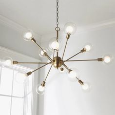 a chandelier hanging from the ceiling in a room with white walls and windows