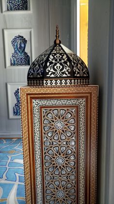 an intricately decorated wooden box on display in a room with blue and white wallpaper