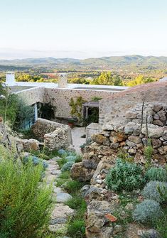 an old stone house surrounded by greenery and rocks