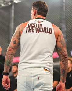 a man with tattoos on his back standing in front of a crowd