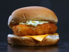 a fried chicken sandwich with cheese and mayonnaise on a black surface, ready to be eaten