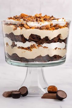 a layered cake with white frosting and chocolate candies on the side, in a glass dish