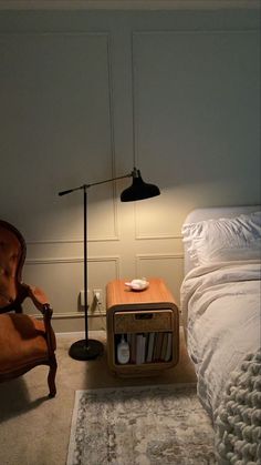 a room with a bed, chair and lamp on the floor next to each other