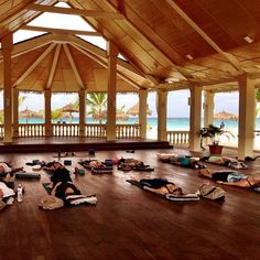 a group of people laying on their stomachs in a large room next to the ocean