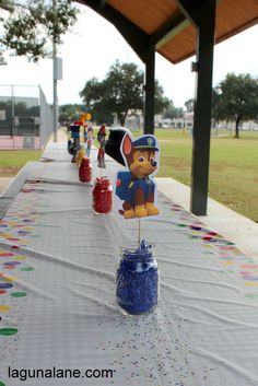 a long table covered in plastic cups and paper decorations with paw patrol characters on them