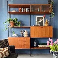 a living room filled with furniture and flowers in vases on top of bookshelves