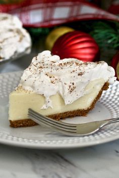 a piece of cheesecake on a plate with a fork and christmas decorations in the background