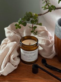 a candle sitting on top of a wooden table next to a potted plant and spoon