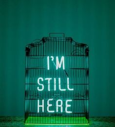 a neon sign that says i'm still here in front of a green background