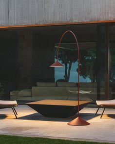 two lounge chairs and a table in front of a large glass window with trees outside