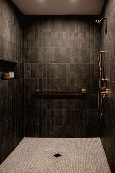 a walk in shower sitting next to a tiled wall and floor with two lights above it