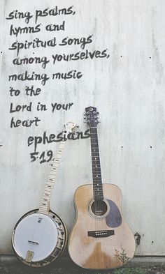 two guitars sitting next to each other in front of a wall with writing on it