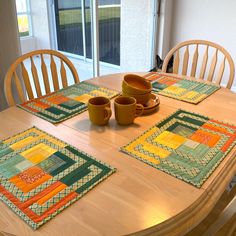 a wooden table topped with place mats and cups