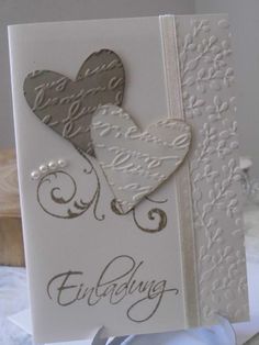 a card with two hearts on it and the word love is written in silver ink