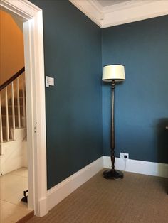 a lamp in the corner of a room with blue walls and carpeted flooring