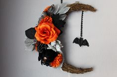 an orange and black flower is hanging on the wall next to a bat shaped decoration