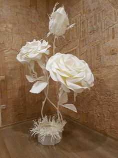 three white roses in a vase on a wooden floor