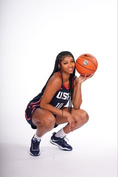 a woman is holding a basketball and posing for a photo in front of a white background