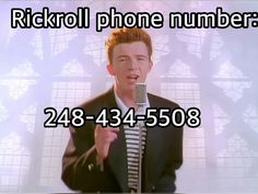 a man holding a microphone in front of a sign that says rickroll phone number