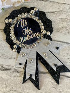 a black and white happy birthday ribbon with flowers in the background on a stone wall