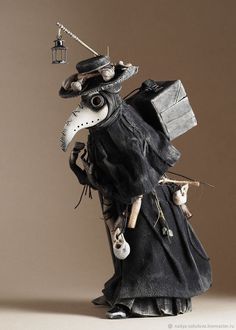 a figurine is dressed in black and holding a box with a bird on it's head