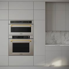 two ovens side by side in a kitchen with white cabinets and marble counter tops