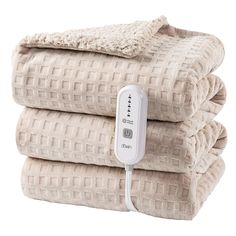 three blankets stacked on top of each other with an electric heating device plugged in