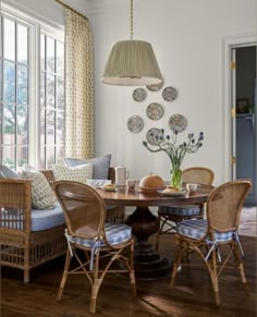 a dining room table with chairs and plates on the wall next to it's windows