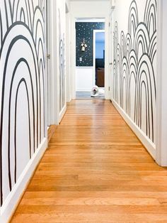 the hallway is decorated with art deco wallpaper and wood flooring, along with white walls