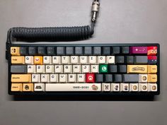 a computer keyboard sitting on top of a table next to a corded phone charger