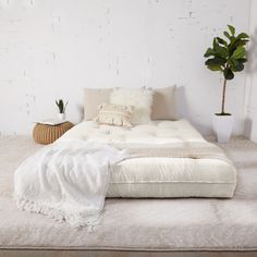 a bed sitting on top of a white floor next to a potted plant