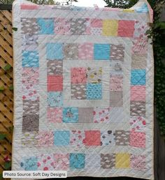 a quilt is hanging on the side of a wooden fence in front of a tree