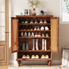 a wooden cabinet filled with lots of pairs of shoes next to a potted plant