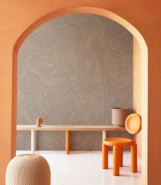 an orange chair sitting next to a white table in a room with a large wall behind it