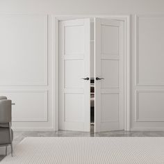 an empty room with white walls and two chairs in front of the open door that leads to another room