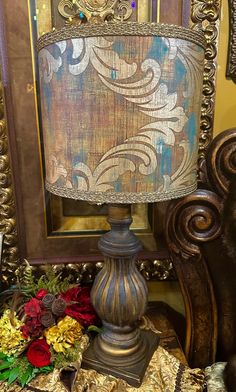 a lamp sitting on top of a wooden table next to a framed photo and flowers