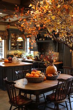 a dining room table and chairs with fall leaves hanging from the ceiling over it in front of an island