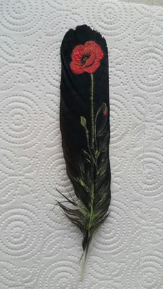 a black feather with a red flower on it