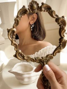 a woman looking at herself in the mirror with her eyes closed and hands holding it