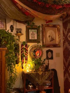 a living room filled with lots of plants and pictures on the wall next to it