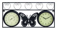 two clocks with butterflies on them are hanging from a wall bracket that is decorated with wrought iron