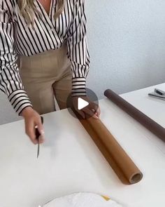 a woman is cutting a piece of wood with a knife on top of the table