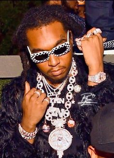 a man wearing sunglasses and some jewelry on his neck